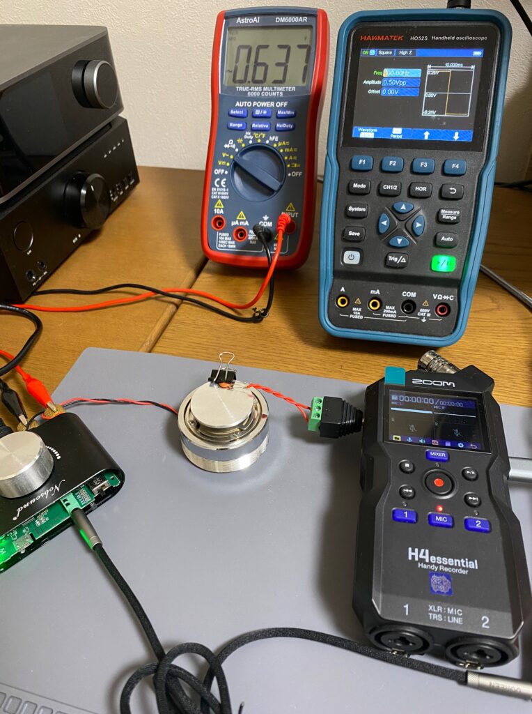 コンデンサを振動スピーカーにクリップで固定して振動させマイクロフォニック音の周波数特性を測定している写真