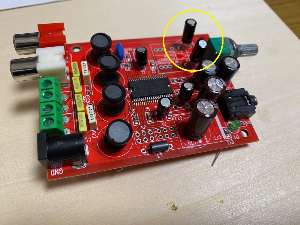 デジタルアンプの入力カップリングコンデンサの写真。黄色い丸がカップリングコンデンサ